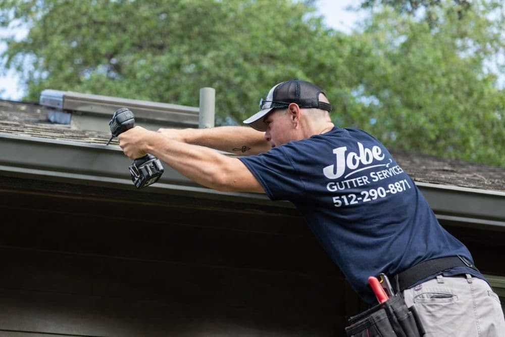 Jobe Gutter Services technician installing gutters on a residential roofline
