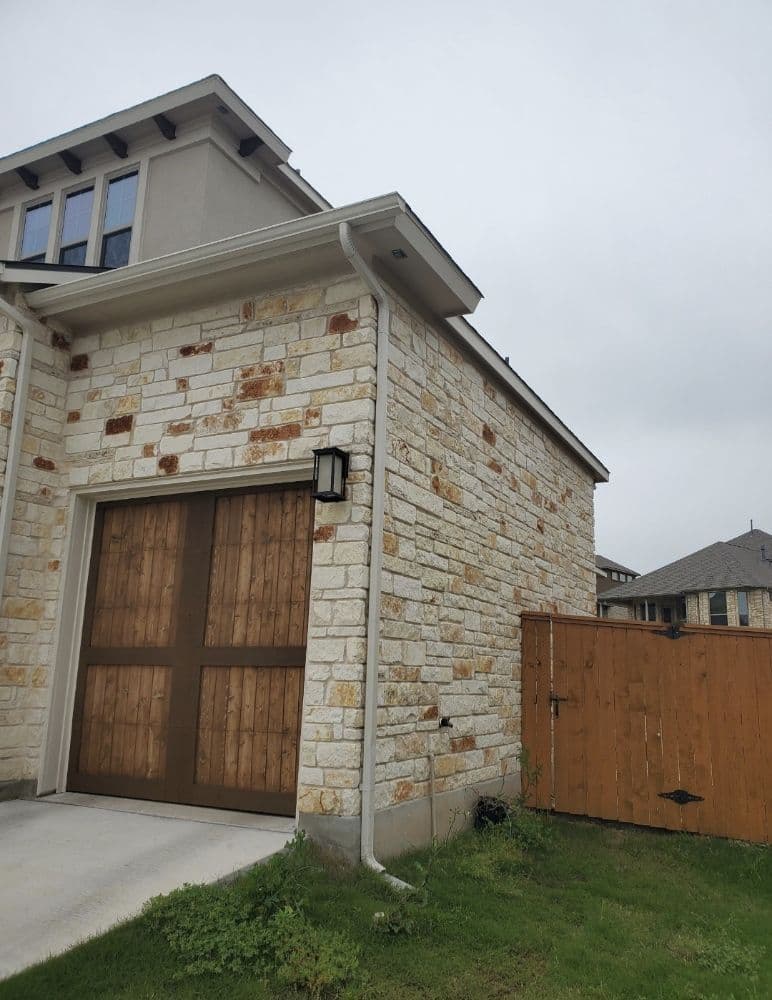 Two-story stone home with gutter and downspout system
